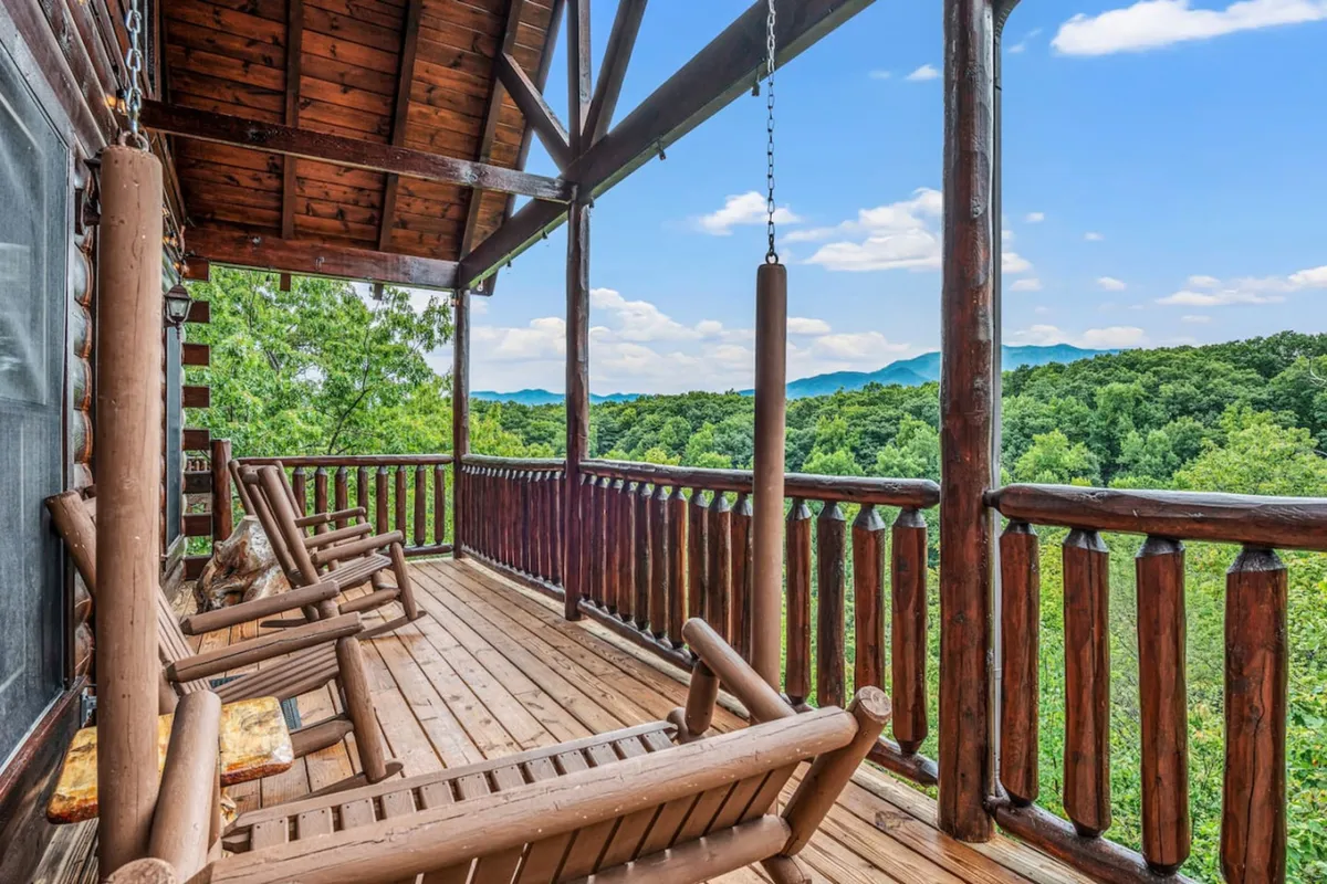 An exterior deck scene with classic wooden rocking chairs overlooking a stunning mountain vista, inviting guests to sit, socialize, and soak in the tranquil views.