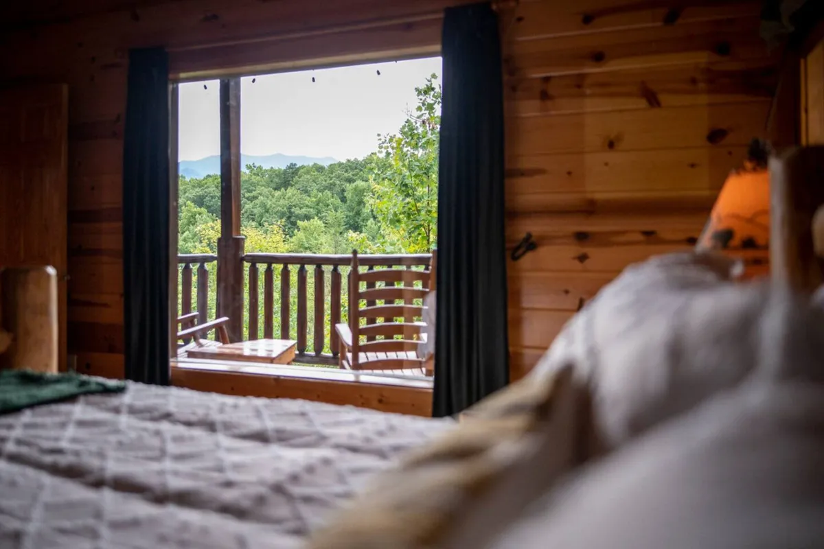 A wooden balcony with comfortable seating offers an elevated vantage point over the Smoky Mountains. The inviting space is designed for quiet mornings with coffee or evenings spent watching the stars, bridging the comfort of the cabin with the majesty of the surrounding wilderness.